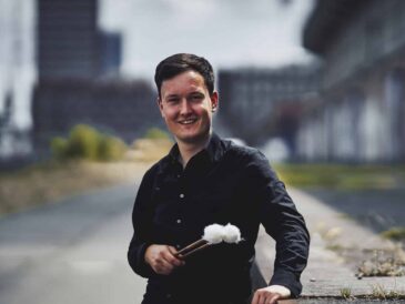 Musician's portrait outdoor, black shirt, holding a pair of timpani mallets